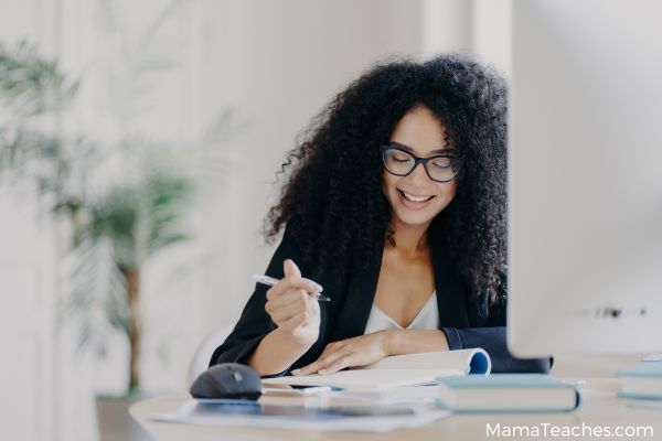 college age woman working on an essay at a desk with books and a computer